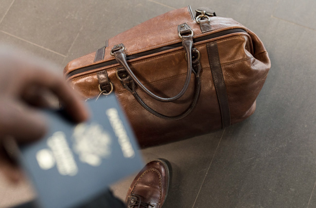A hand holding a passport over a travel bag