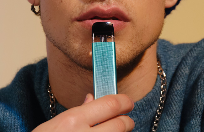 Image of a man holding a Vaporesso Xros vape device to his mouth
