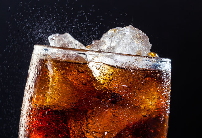Glass of pepsi filled with ice on a dark background.