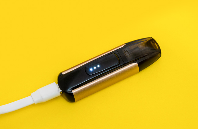 Pod device charging on a yellow background.