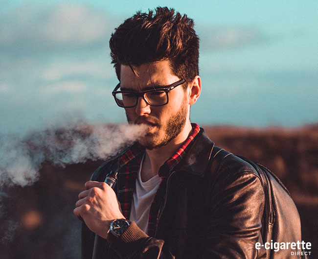 A man holding a vape device with vapour coming from his mouth