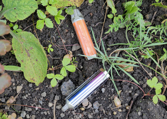 Discarded disposable vapes laying in grass