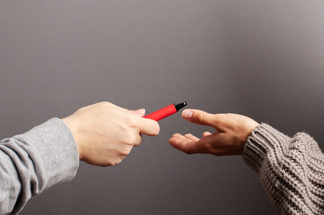 A person handing a disposable vape to another person