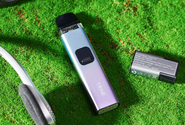 Innokin Trine vape device on grass with external battery next to it.