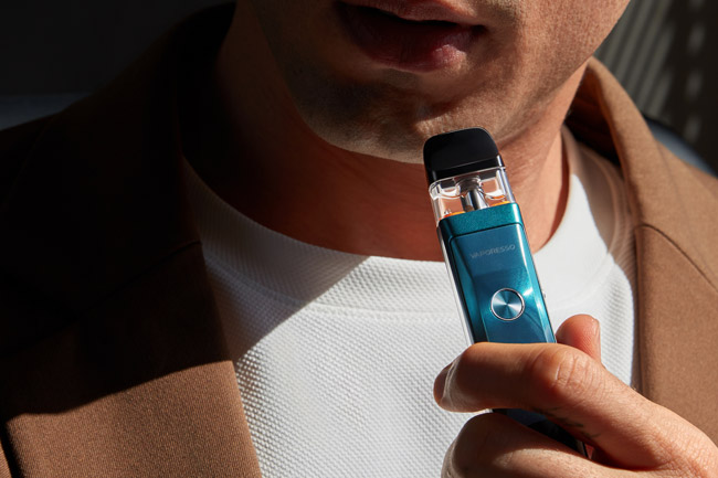 Man holding a blue Xros Pro vape device.