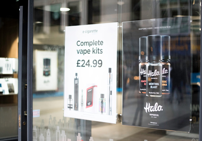 Promotional posters in a vape shop window.