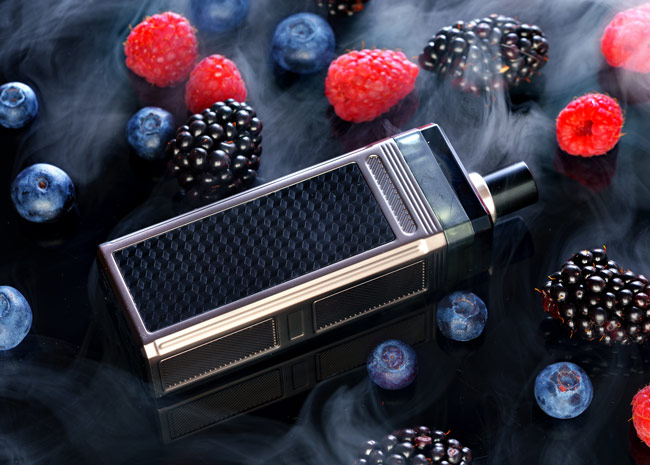 A vape device surrounded by berries.