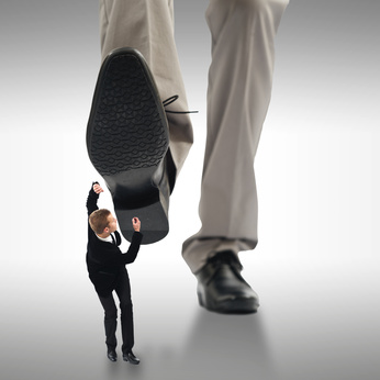 Large foot coming down on small man. 